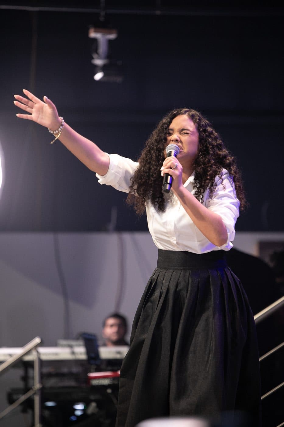 Elizabet María adorando con una mano levantada